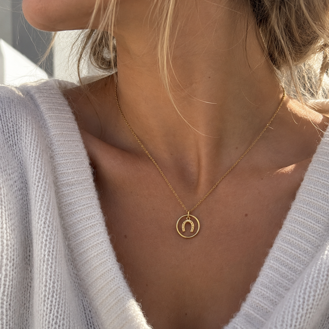 Collier équestre doré porté par une femme avec pendentif fer à cheval – Equestrian Shop